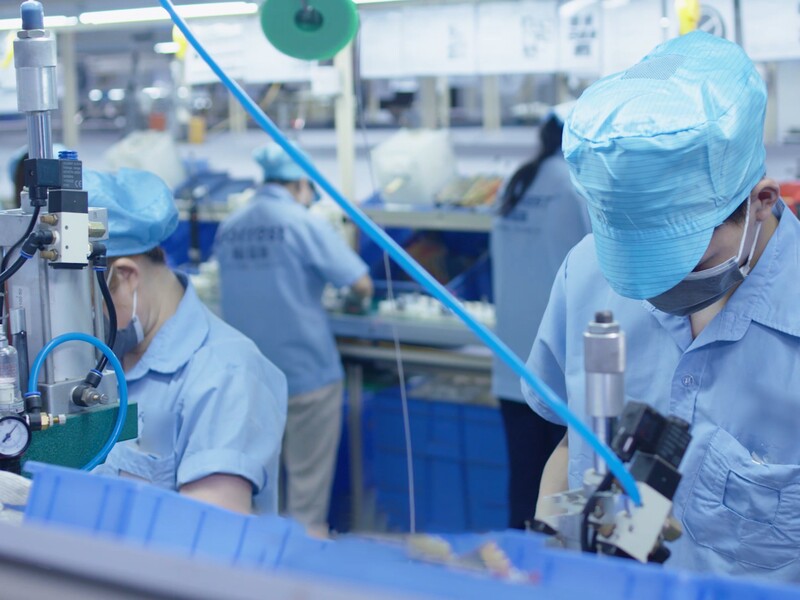 Worker in protective clothing assembling electronic components on a Forrest production line.